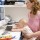 Mother holding child while working on computer